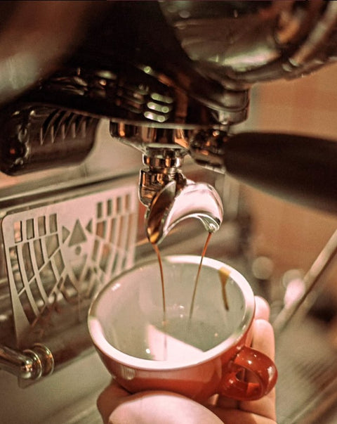 Coffee falling from espresso machine into a coffee pot